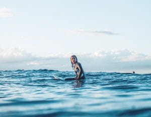 une surfeuse en combinaison sur une planche de surf dans la mer