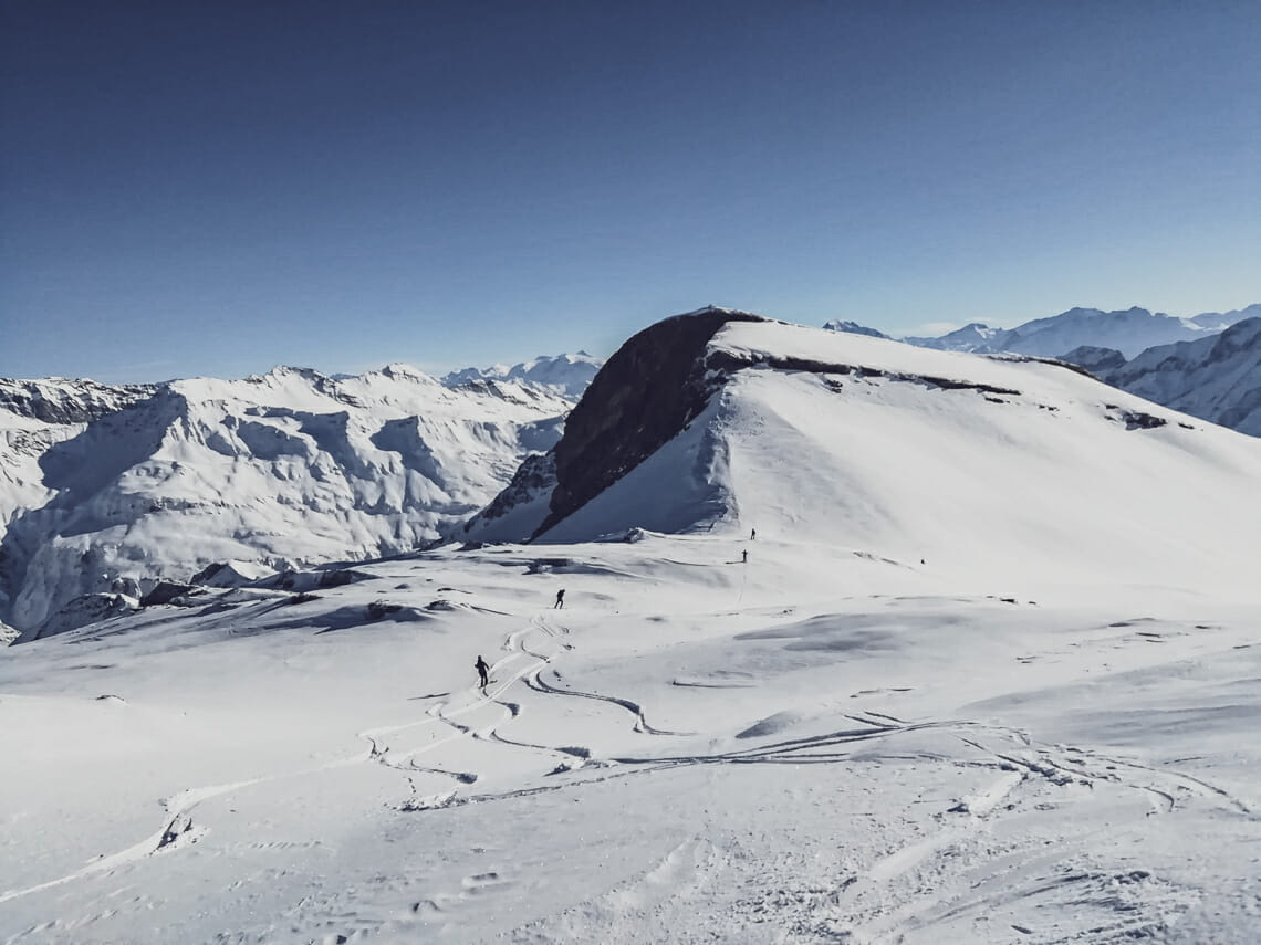 des personnes descendent au loin en ski une montagne enneigée