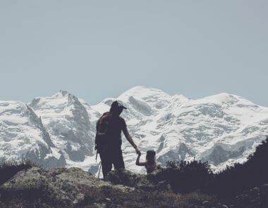 Une femme tient sa fille par la main devant la montagne enneigée