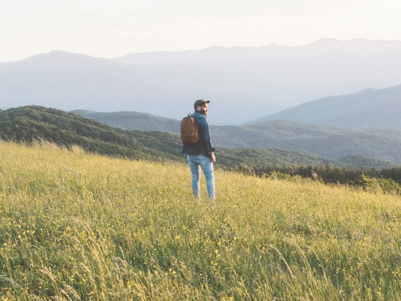 un homme avec un sac à dos se balade dans la campagne