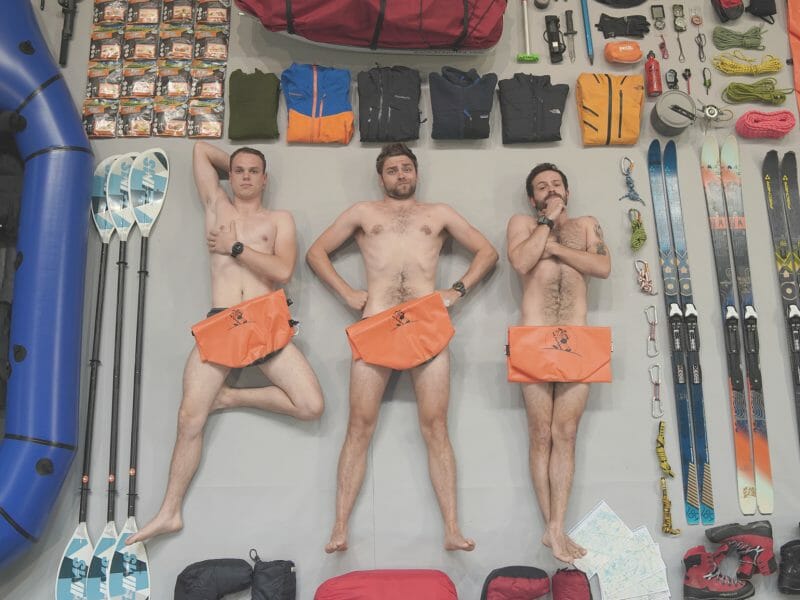 3 hommes engagés posent nus allongés à côté de leur matériel d'expédition vers le Cap Nord