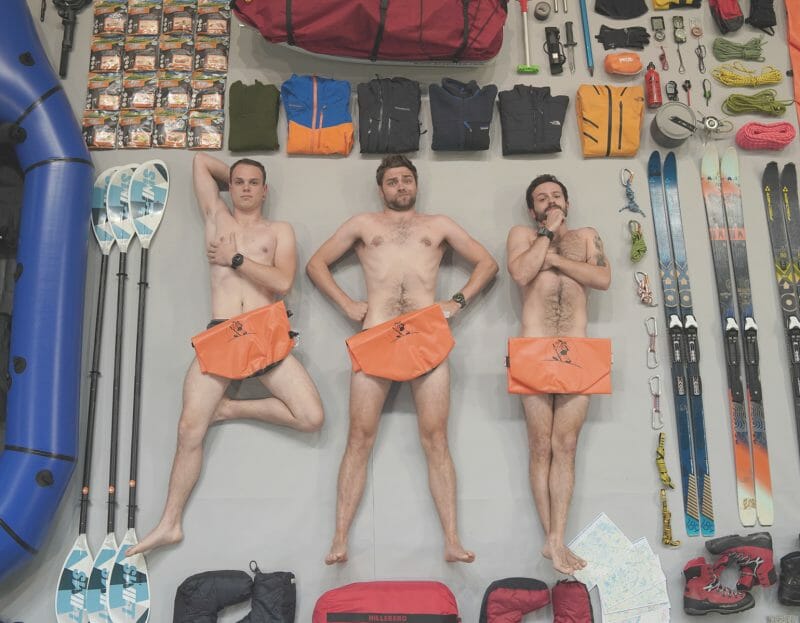 3 hommes engagés posent nus allongés à côté de leur matériel d'expédition vers le Cap Nord