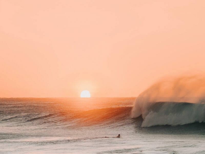Le soleil se lève sur la mer alors qu'un surfeur s'apprête à affronter les vagues