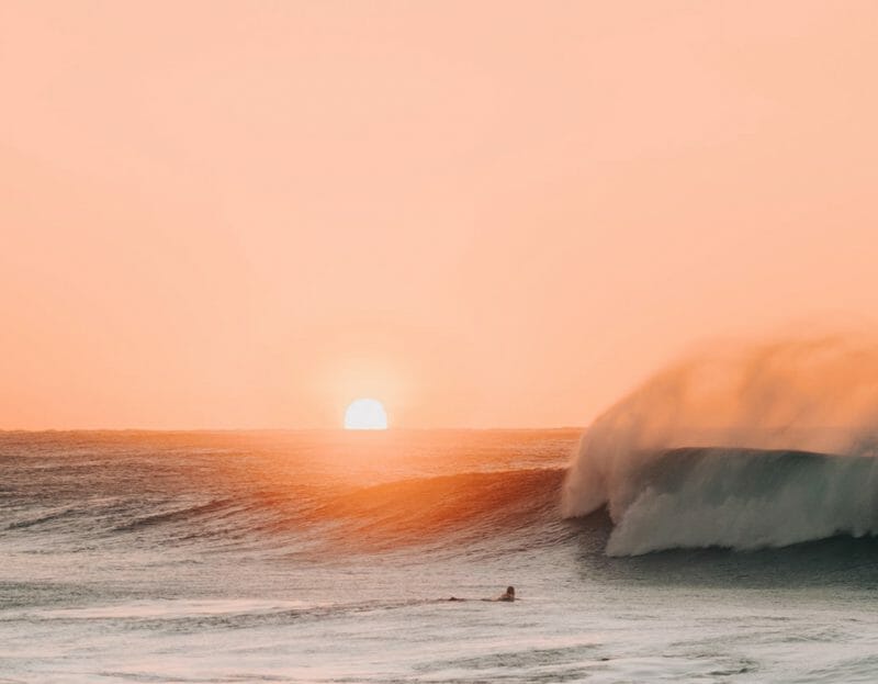 Le soleil se lève sur la mer alors qu'un surfeur s'apprête à affronter les vagues