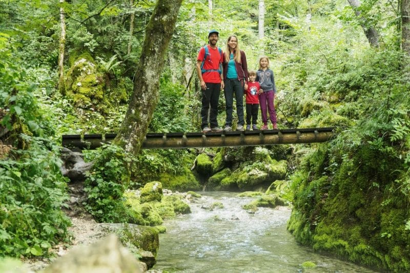 Une famille sur un pont au dessus d'un ruisseau en montagne