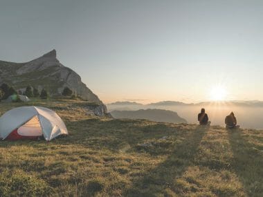 un groupe d'amis devant leur tente dans les alpes