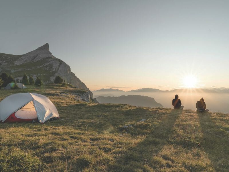 un groupe d'amis devant leur tente dans les alpes