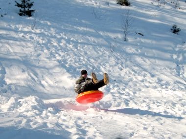 Un homme qui fait de la luge sur la neige avec une bouée.