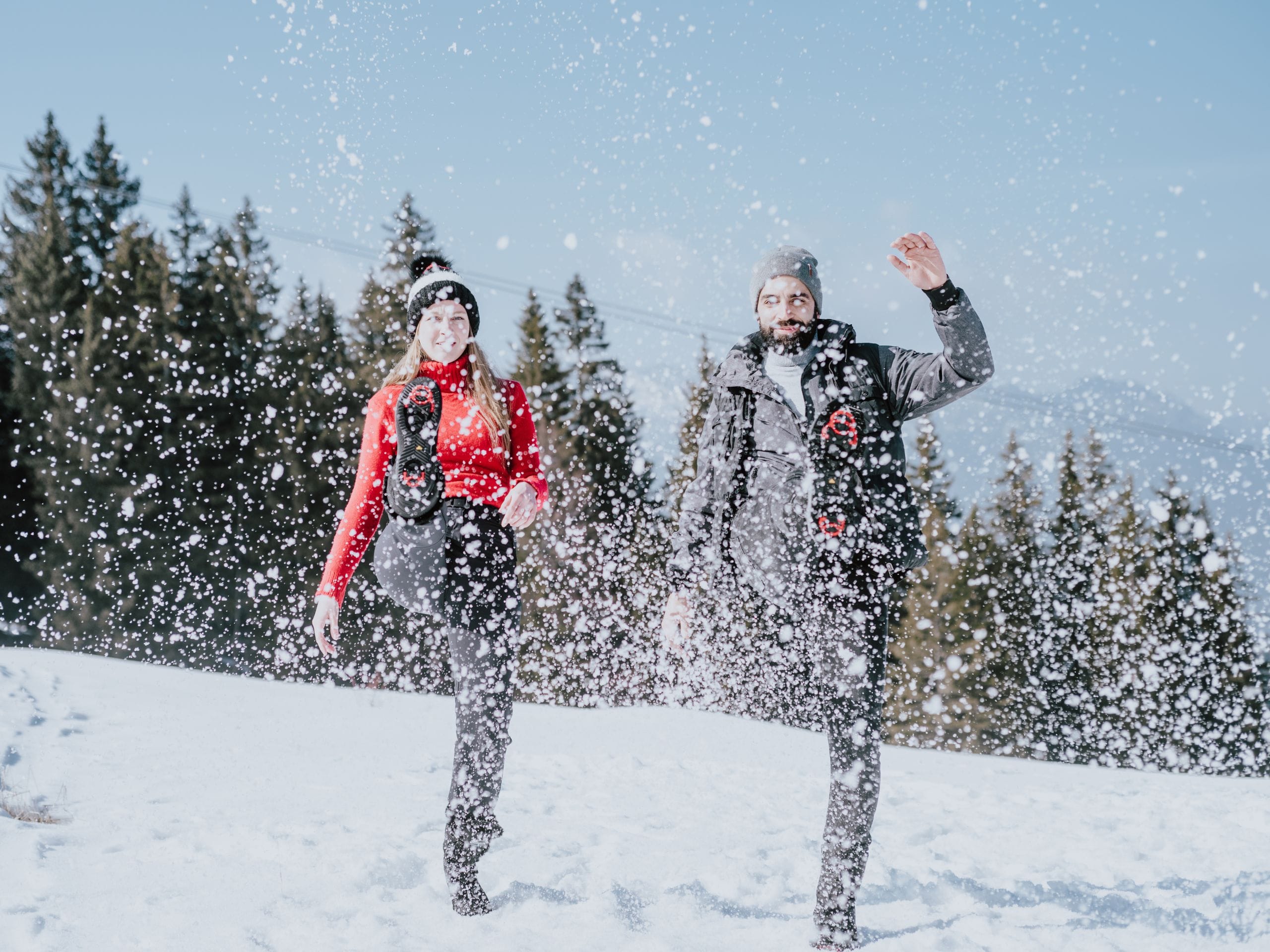 Deux personnes qui projettent de la neige avec leurs bottes. 