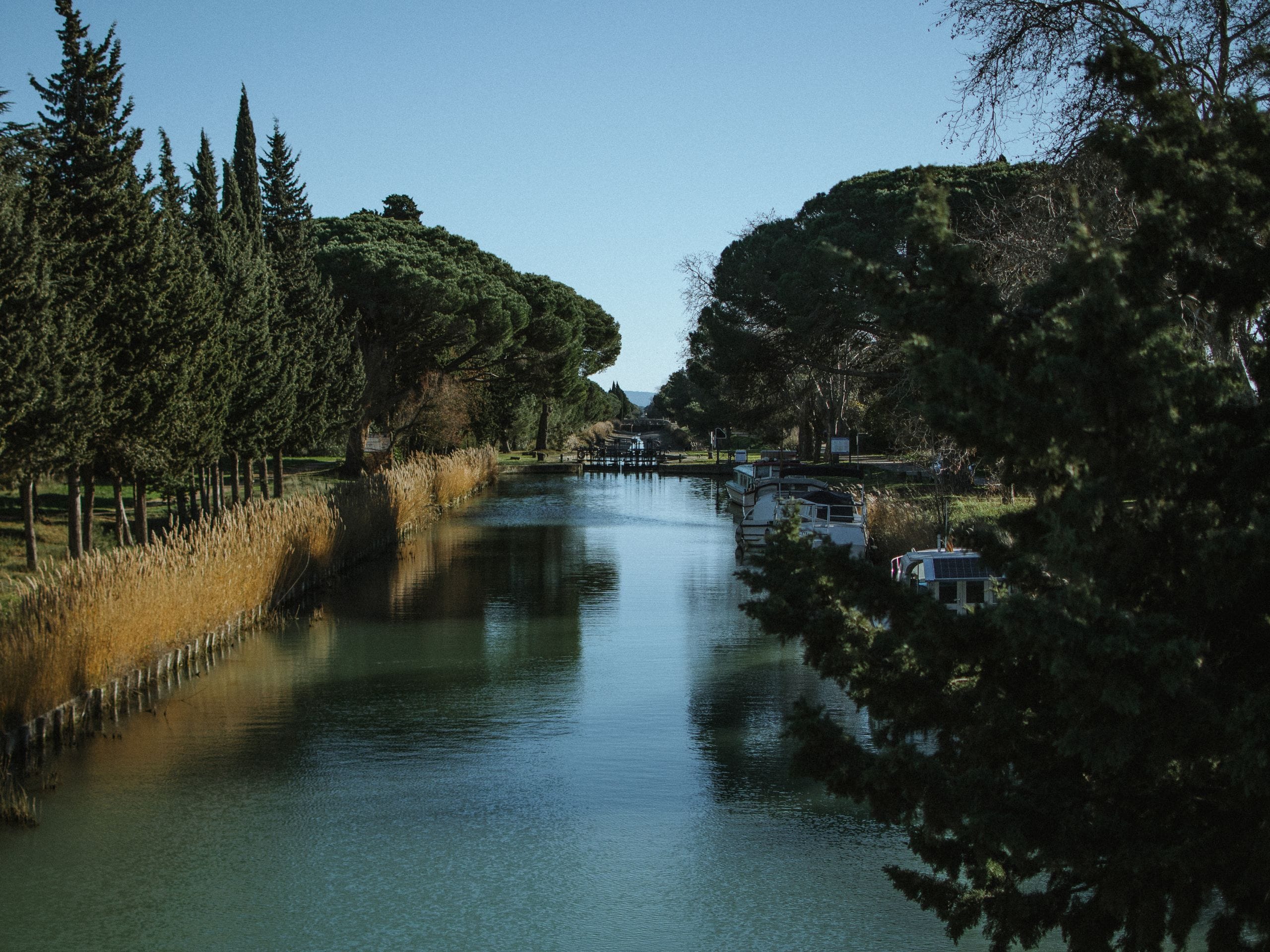 Jolie vue sur le canal de l'Aude avec des bateaux accostés sur le côté. 