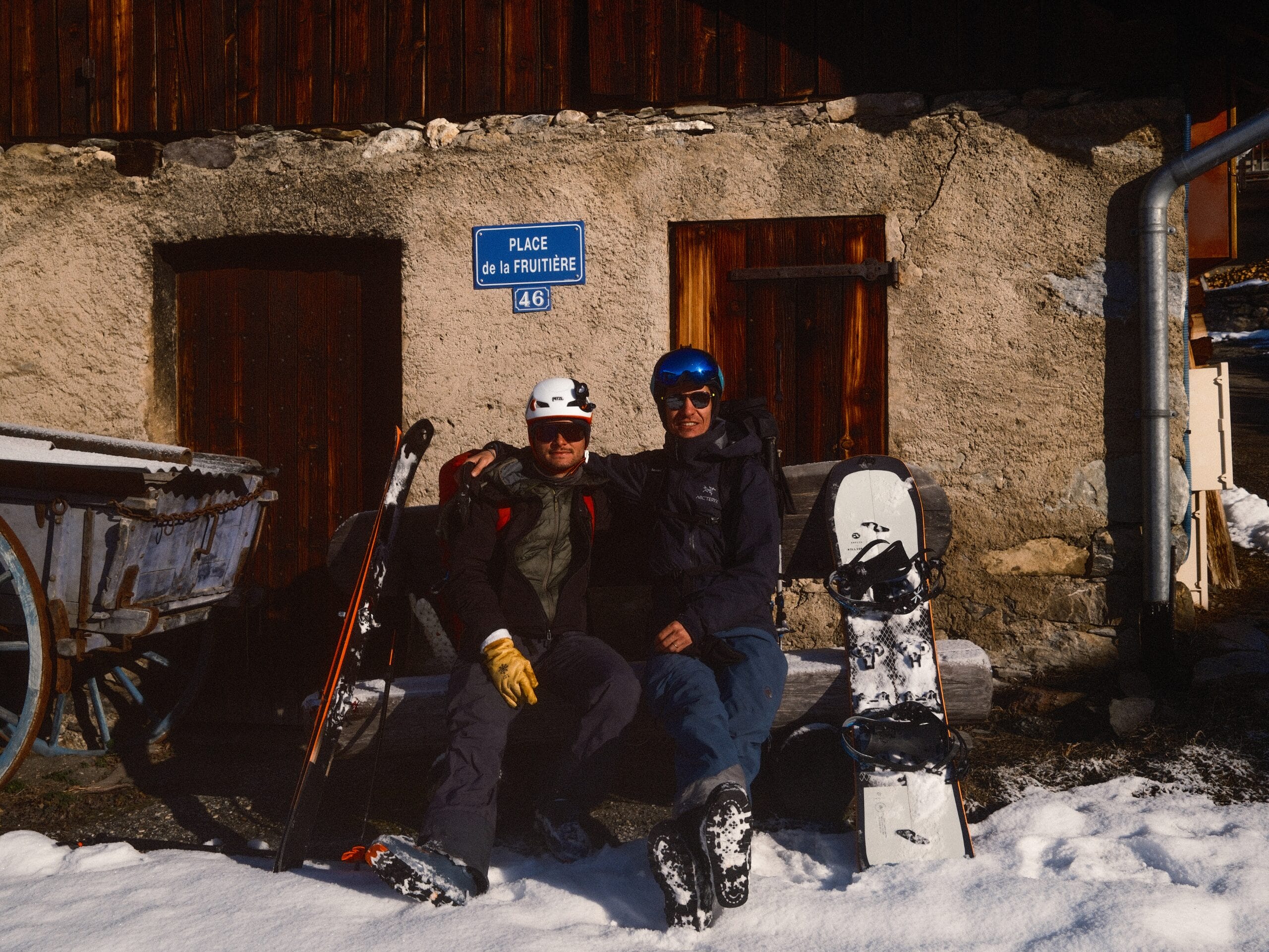 Deux amis assis sur un banc au soleil devant une maison dans le Beaufortain. 