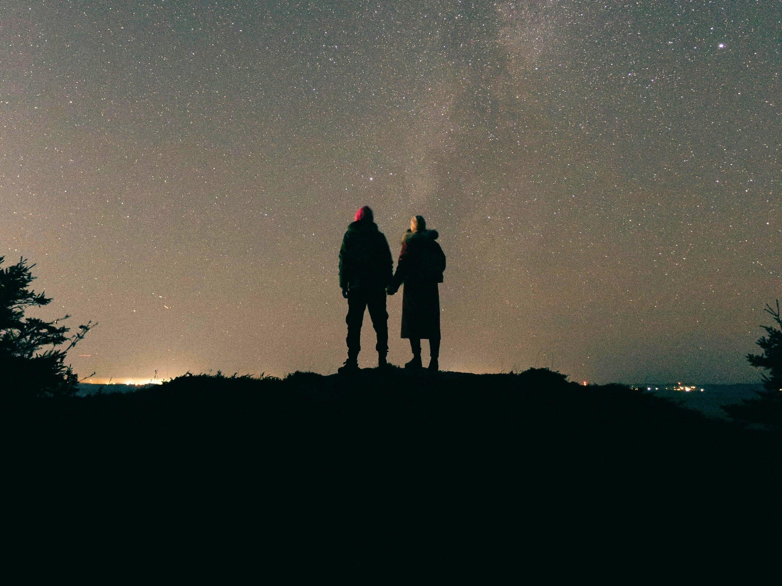 Deux personnes en haut d'une colline qui regardent les étoiles. 