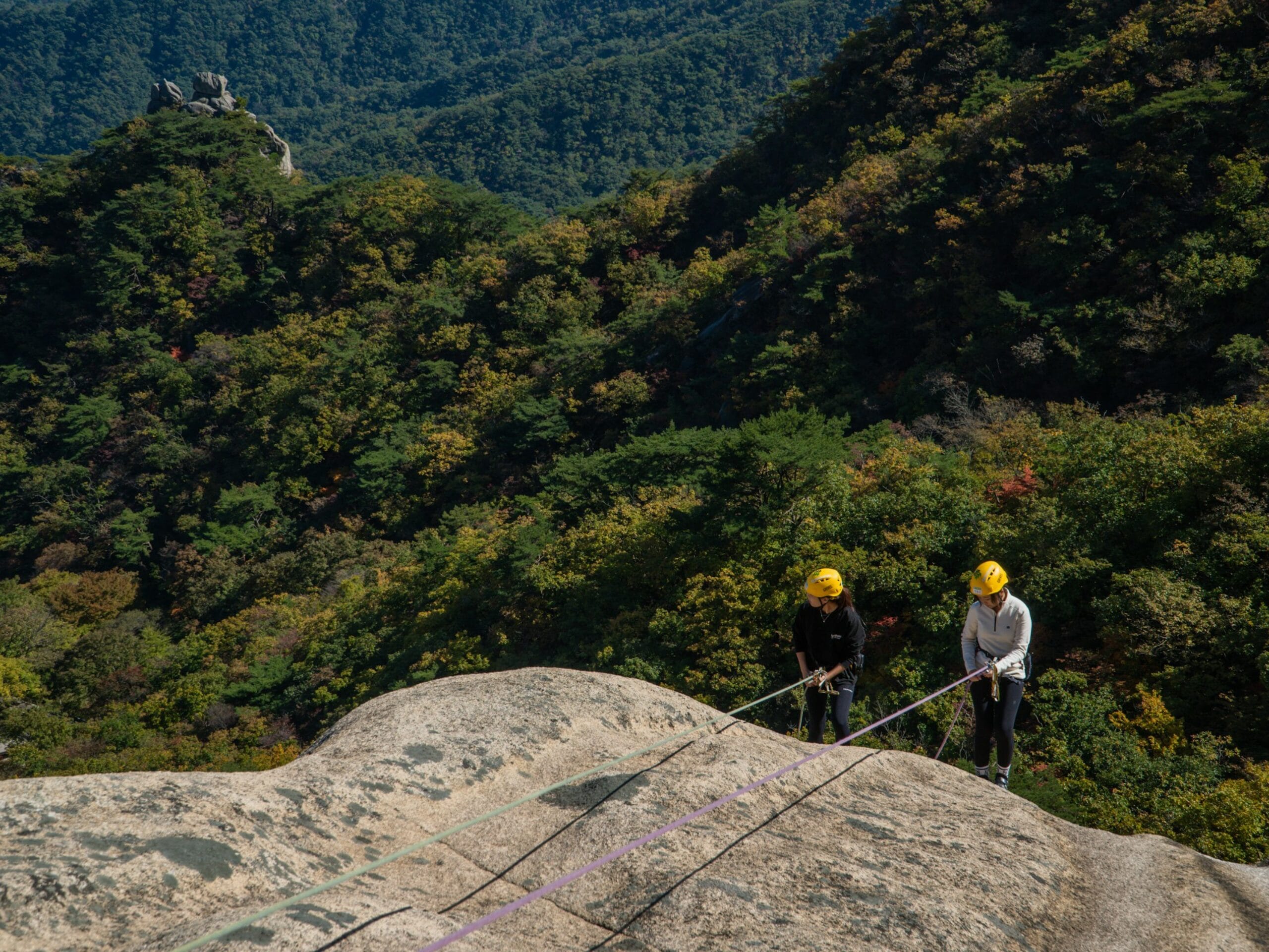 Deux femmes qui descendent en rappel sur une paroi en escalade. 