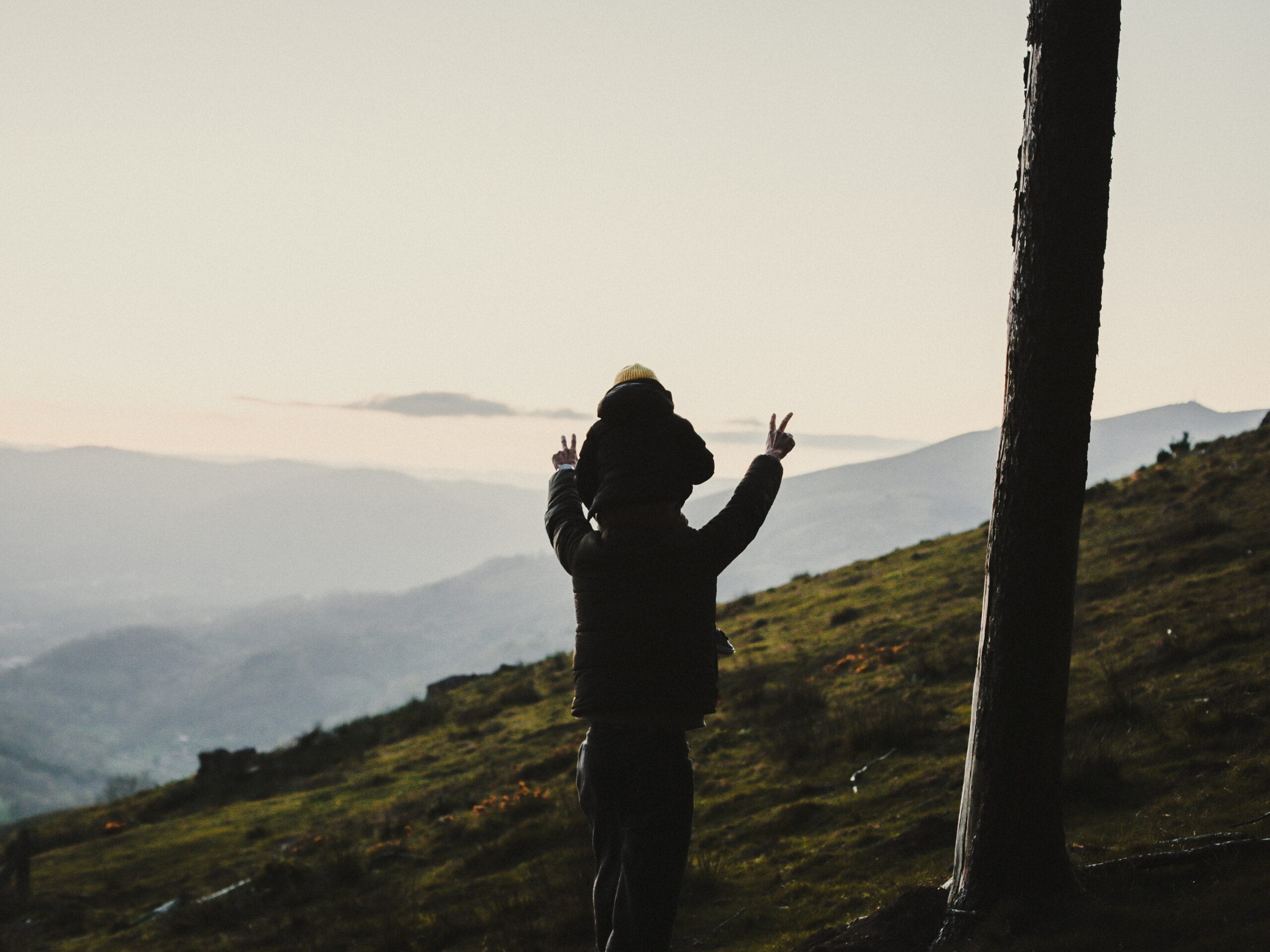 Enfant sur les épaules d'un adulte devant la montagne