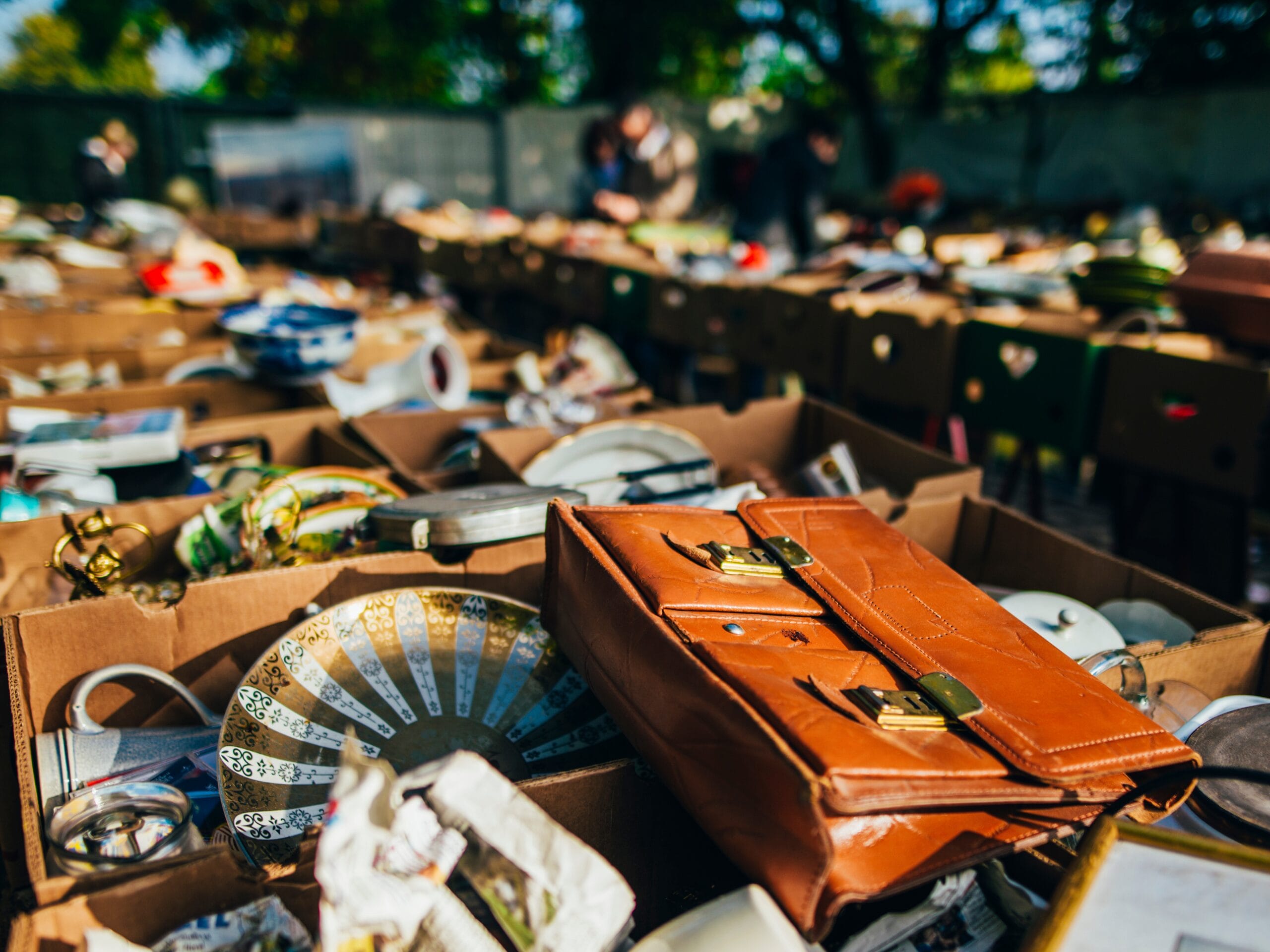 Une brocante de village avec des objets variés dans des cartons.