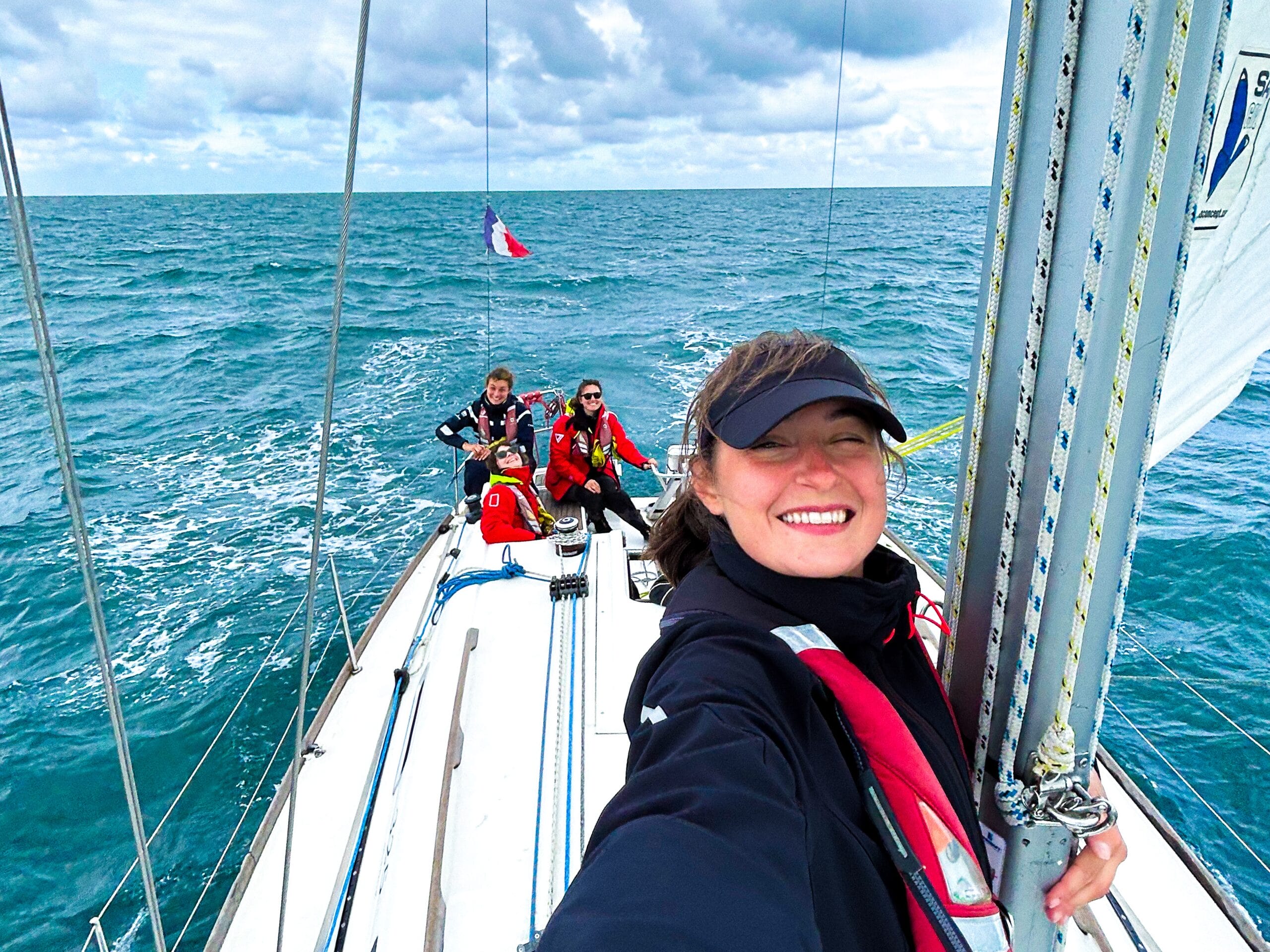 Laura sur son voilier avec des stagiaires à bord en fond