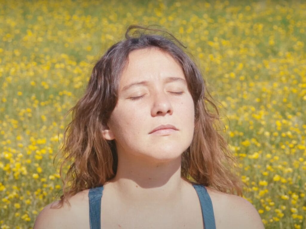 Screenshot de la vidéo "Vivre avec une maladie mentale", visage de Léa Vigier dans un joli champ jaune de colza